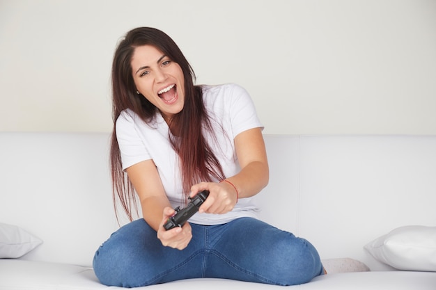 Jolie femme jouer à des jeux vidéo sur un canapé