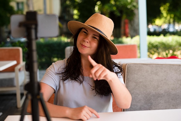 Jolie femme joyeuse à l'extérieur assis avec trépied et smartphone