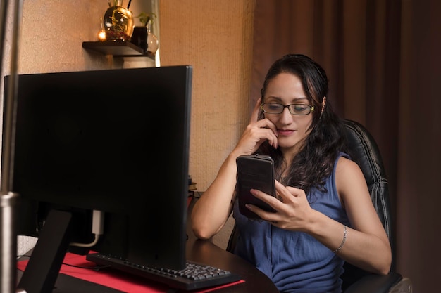 Jolie femme latine d'âge moyen utilisant un téléphone portable dans son espace de travail