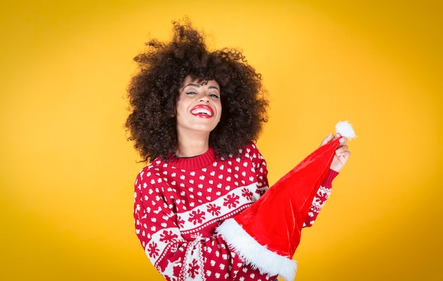 jolie femme latine hispanique, avec bonnet de noel, fond jaune