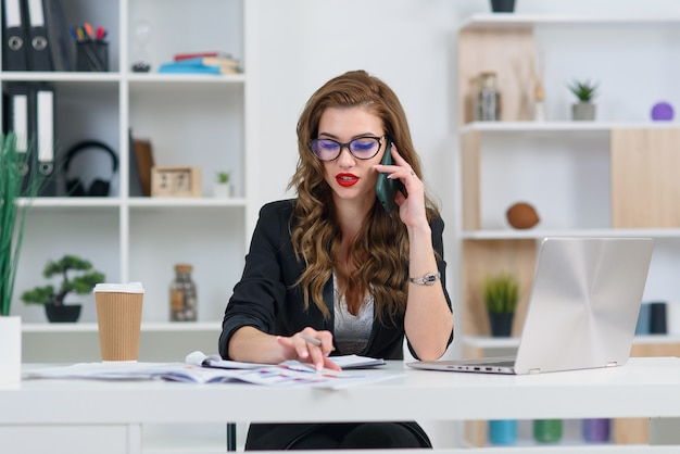 Jolie femme à lunettes, avoir une conversation téléphonique d'affaires