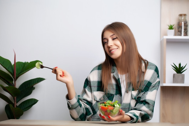 Jolie femme mange une salade de légumes avec beaucoup de vitamines