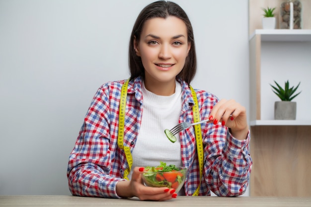 Jolie femme mange une salade de légumes avec beaucoup de vitamines