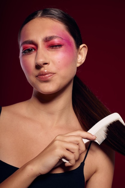 Jolie femme avec un maquillage lumineux peignant ses cheveux soins personnels