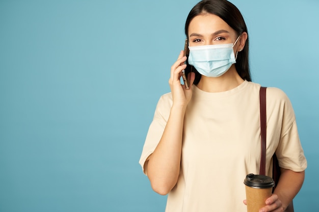 Jolie femme en masque facial à l'aide de smartphone