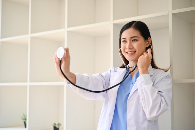 Jolie femme médecin asiatique en robe blanche avec un stéthoscope