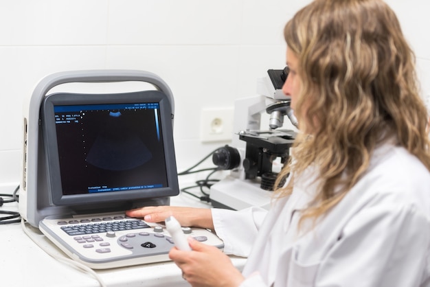 Jolie femme médecin posant en train de faire une sonographie.