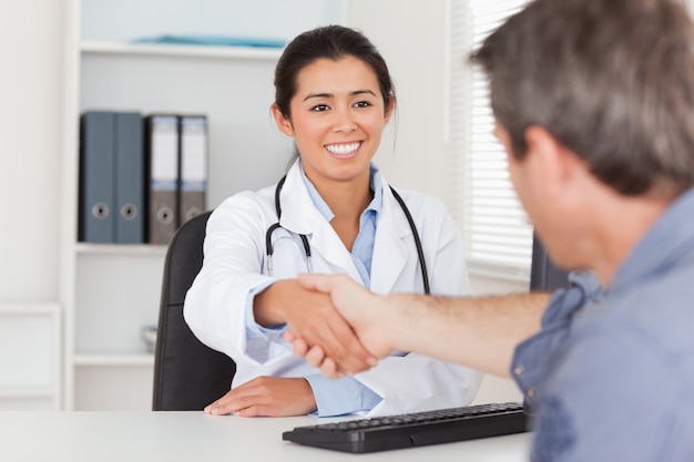 Jolie femme médecin secouant les mains d&#39;un patient