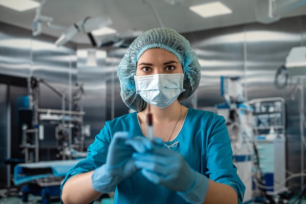 Jolie femme médecin tenant une seringue dans la salle d'opération pour le patient