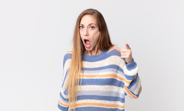 Jolie femme mince pointant vers la caméra avec une expression agressive en colère ressemblant à un patron furieux et fou