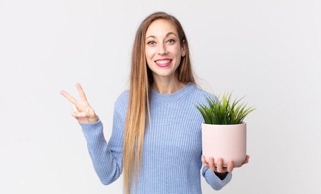 Jolie femme mince tenant une plante d'intérieur décorative