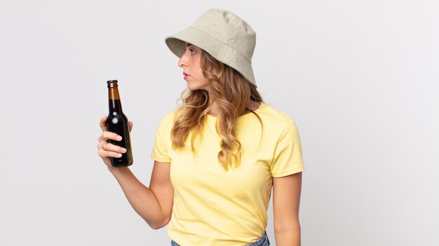 Jolie femme mince sur la vue de profil pensant imaginer ou rêvasser et tenant un concept d'été de bière