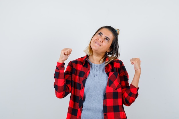 Jolie femme montrant le geste du gagnant dans des vêtements décontractés et l'air heureux. vue de face.