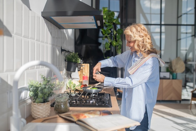 Jolie femme mûre blonde faisant cuire dans la cuisine