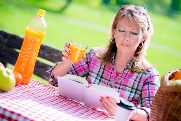 Jolie femme mûre lisant un livre dans le parc