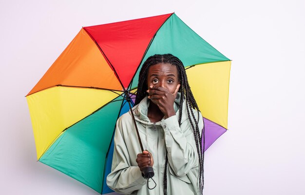 Jolie femme noire couvrant la bouche avec les mains avec un choc. concept de parapluie