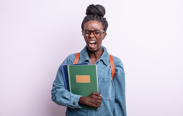 Jolie femme noire criant agressivement, l'air très en colère. étudiant avec le concept de livres