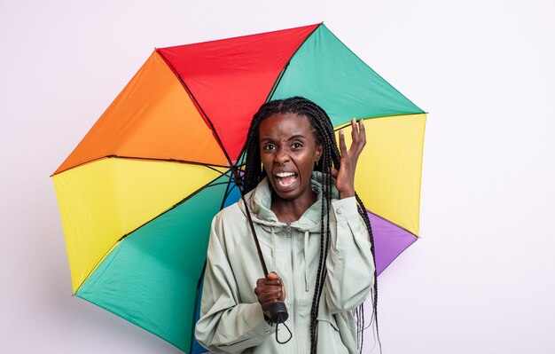 Jolie femme noire criant avec les mains en l'air. concept de parapluie