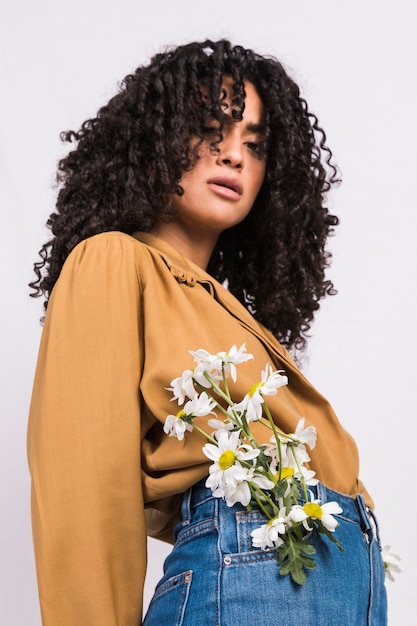 Jolie femme noire avec des fleurs dans la poche d'un jean