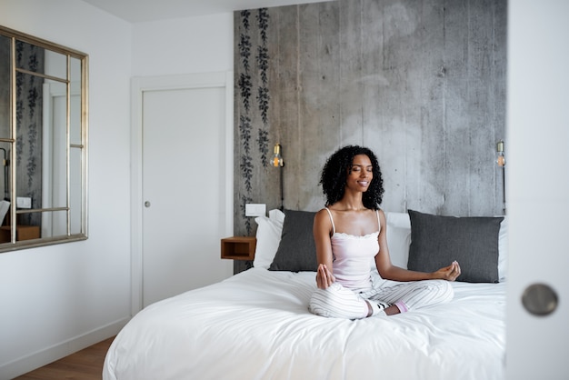 Photo jolie femme noire sur lit méditant