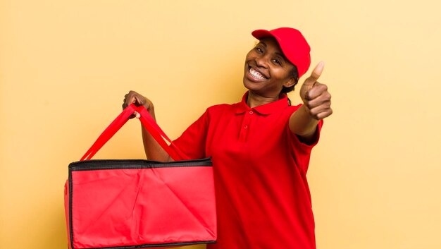 Jolie femme noire se sentant fière de sourire positivement avec les pouces vers le haut