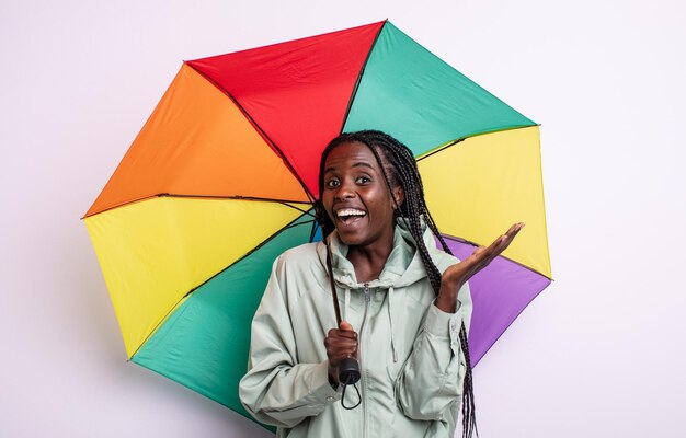 Jolie femme noire se sentant heureuse et étonnée de quelque chose d'incroyable concept de parapluie