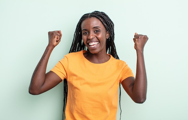 Jolie femme noire se sentant heureuse, positive et réussie, célébrant la victoire, les réalisations ou la bonne chance