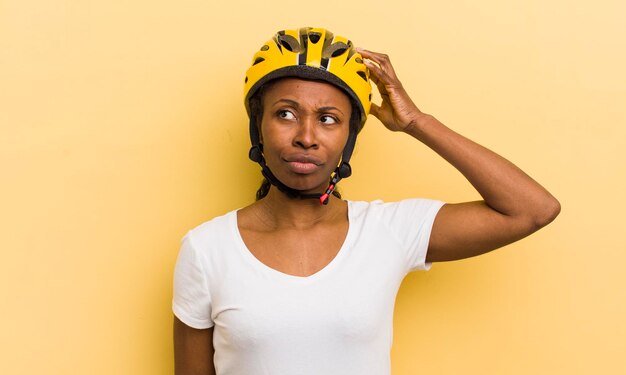 Jolie femme noire se sentant perplexe et confuse se grattant la tête