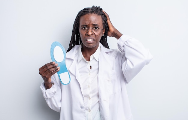 Jolie femme noire se sentant stressée anxieuse ou effrayée avec les mains sur la tête concept de podologue