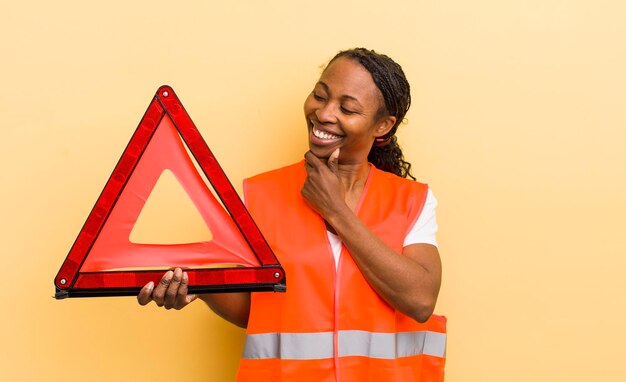 Jolie femme noire souriante avec une expression heureuse et confiante avec la main sur le menton