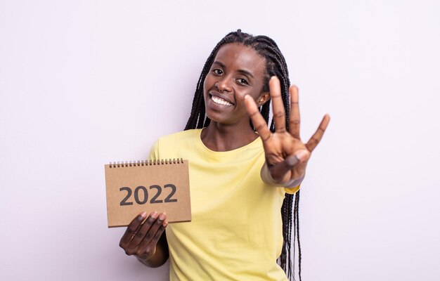 Jolie femme noire souriante et semblant amicale, montrant le numéro quatre. concept de calendrier 2022