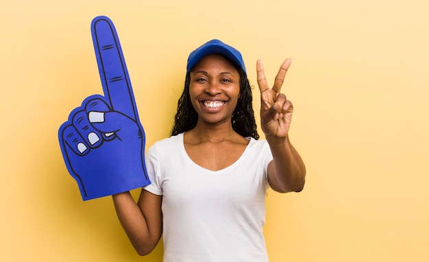 Jolie femme noire souriante et semblant heureuse gesticulant victoire ou paix