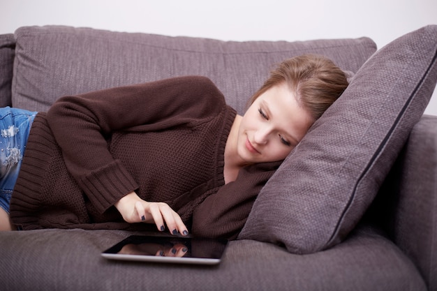 Jolie femme avec ordinateur portable sur le canapé