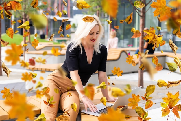 Jolie femme avec ordinateur portable dans le parc en automne.