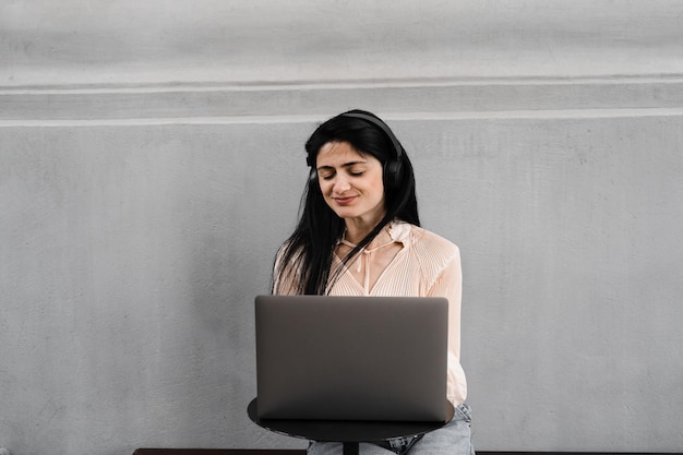 Jolie femme avec un ordinateur portable et des écouteurs travaillant en ligne sur le travail à distance et écouter de la musique Adorable fille géorgienne profite de sa vie en écoutant de la musique et en discutant avec des amis