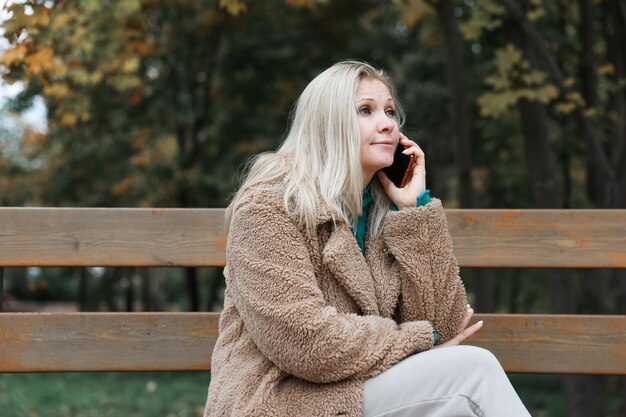 Une jolie femme parlant au téléphone dans un parc en automne