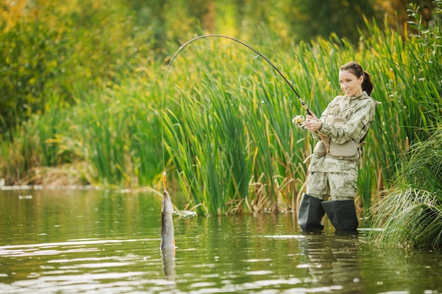 Jolie femme pêche sur la rivière