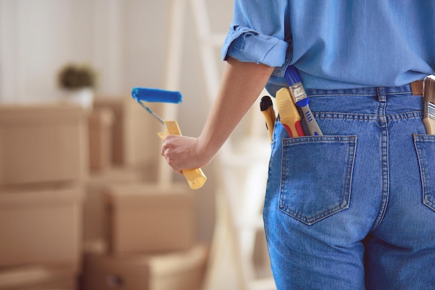 Jolie femme peignant le mur intérieur de la maison avec un rouleau à peinture