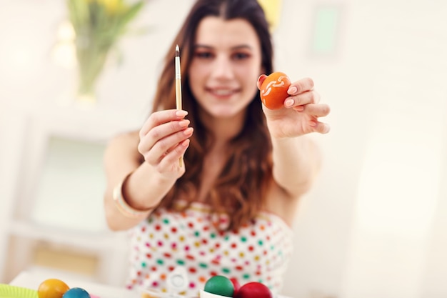 Jolie femme peignant des oeufs de Pâques à la maison