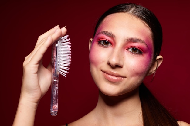 Jolie femme avec un peigne à la main maquillage lumineux posant le modèle de studio d'émotions de mode