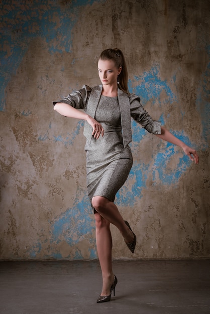 Jolie femme posant dans une robe sur un mur de grunge