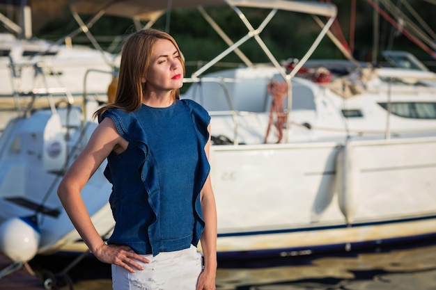 Jolie femme posant sur la marina lors d'une journée d'été ensoleillée au bord de la rivière