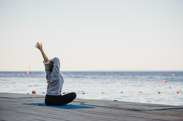 Jolie femme pratiquant le yoga au bord d'un lac