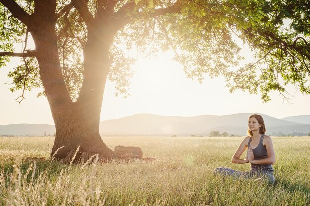 Jolie femme pratique le yoga dans la nature en été