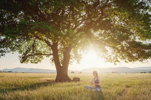 Jolie femme pratique le yoga dans la nature en été