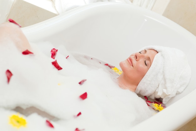 Jolie femme prenant un bain relaxant avec une serviette sur sa tête