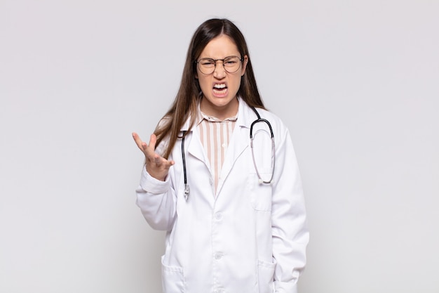 Jolie femme qui a l'air en colère, agacée et frustrée de crier wtf ou qu'est-ce qui ne va pas avec toi