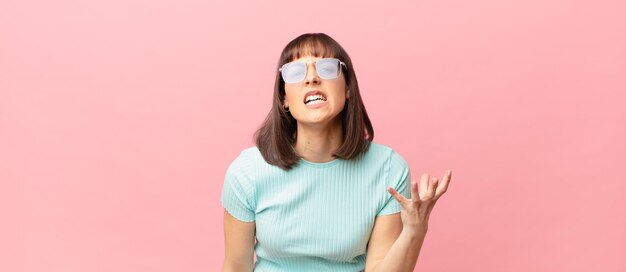 Jolie femme qui a l'air en colère, agacée et frustrée de crier wtf ou qu'est-ce qui ne va pas avec toi