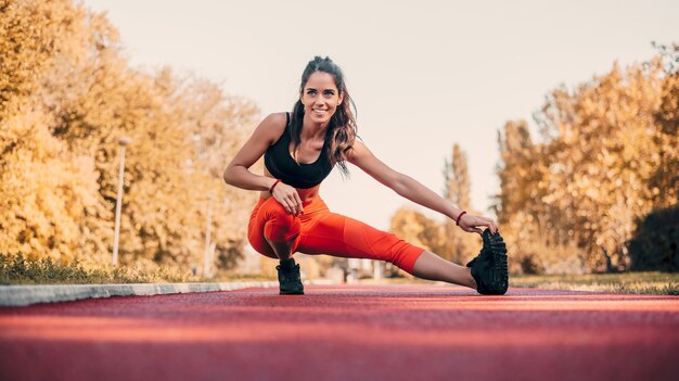 Jolie femme qui s&#39;étend avant la condition physique et l&#39;exercice.