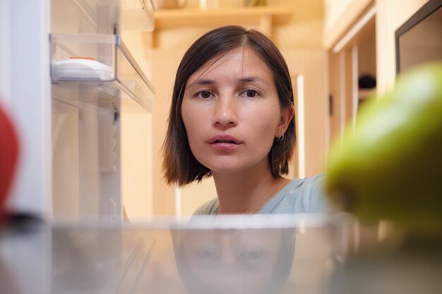 Jolie femme à la recherche de nourriture dans un réfrigérateur
